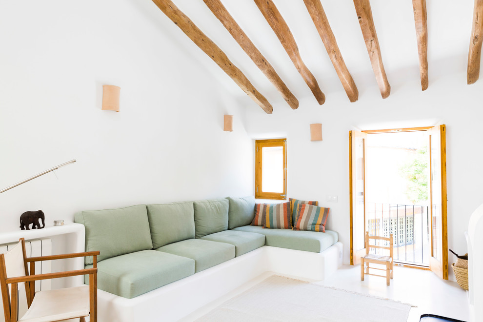 This is an example of a mediterranean open concept living room in Barcelona with white walls and white floor.