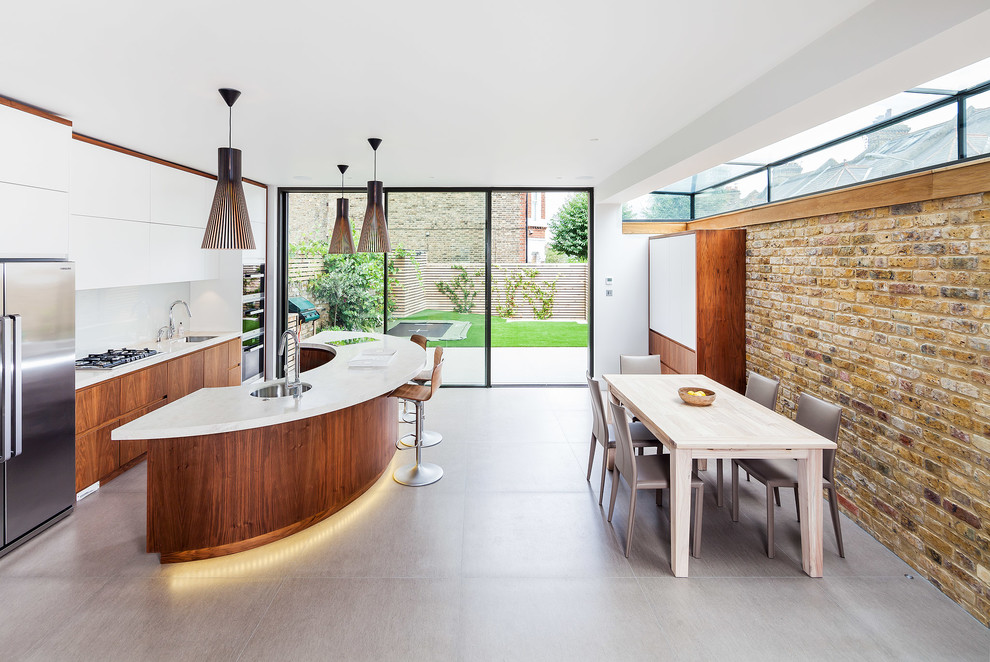 Photo of a large contemporary galley eat-in kitchen in London with an undermount sink, flat-panel cabinets, medium wood cabinets, white splashback, stainless steel appliances and with island.