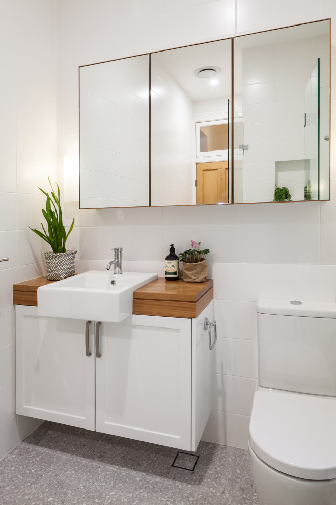 Design ideas for a small scandinavian bathroom in Sydney with shaker cabinets, white cabinets, a corner shower, a one-piece toilet, white tile, porcelain tile, white walls, porcelain floors, a drop-in sink, wood benchtops, grey floor, a hinged shower door, brown benchtops, a niche, a single vanity and a floating vanity.