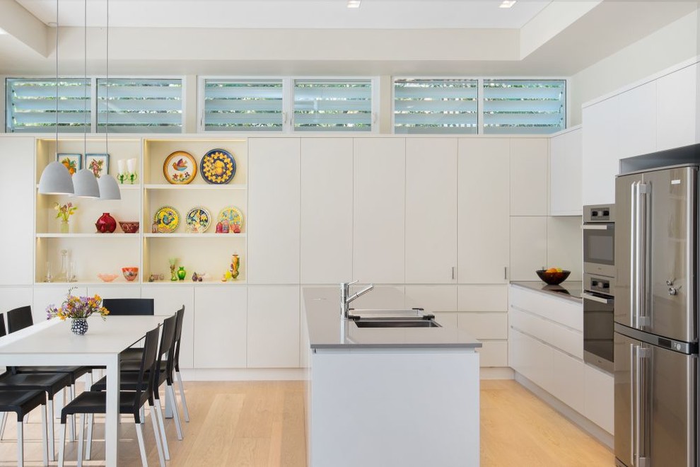 Design ideas for a small contemporary galley eat-in kitchen in Sydney with an undermount sink, flat-panel cabinets, white cabinets, stainless steel appliances, light hardwood floors and with island.