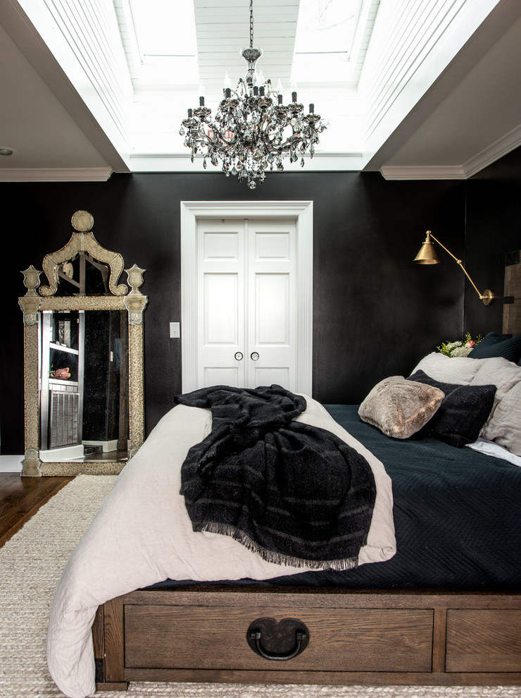 This is an example of a large transitional master bedroom in Nashville with black walls, dark hardwood floors, a standard fireplace, a brick fireplace surround and brown floor.