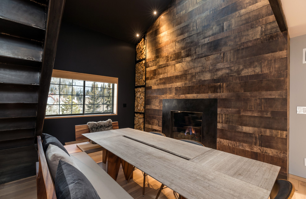 Photo of a large country open plan dining in Denver with multi-coloured walls, light hardwood floors, a standard fireplace, a wood fireplace surround and brown floor.