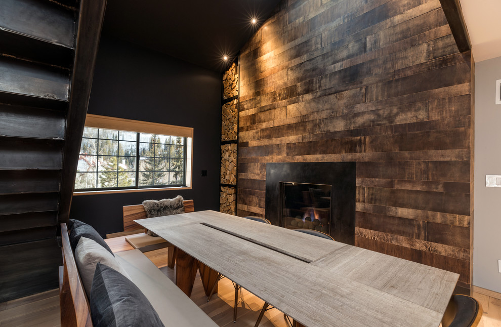 Great Room's Dining Area with a Rustic Fireplace - In this side of the room, a black wall matching with the wood materials around the fireplace, offer a warm and cozy ambiance for a cold night. While the light colored table and chairs that contrasts the wall, makes a light and clean look. The entire picture shows a rustic yet modish appearance of this mountain home.

Built by ULFBUILT. Contact us today to learn more.