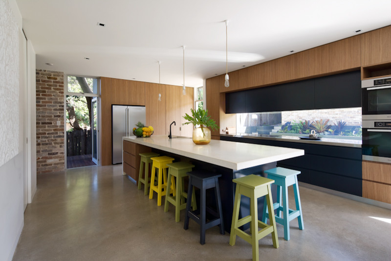This is an example of a mid-sized contemporary galley eat-in kitchen with a double-bowl sink, medium wood cabinets, concrete benchtops, white appliances, concrete floors and with island.