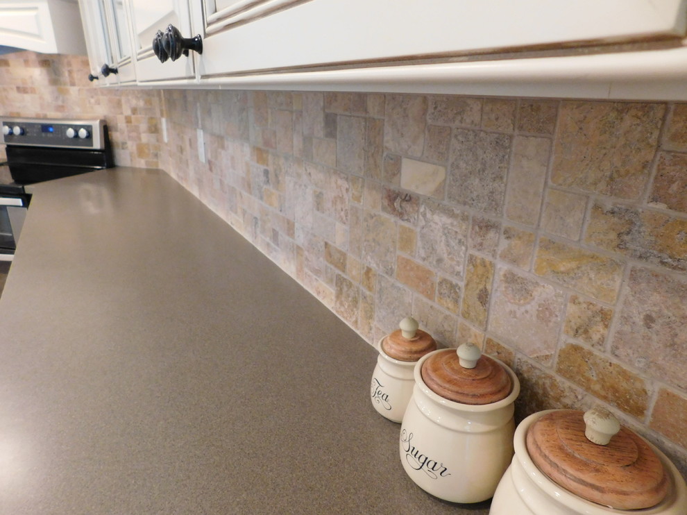Mid-sized transitional galley vinyl floor enclosed kitchen photo with a farmhouse sink, raised-panel cabinets, beige cabinets, solid surface countertops, multicolored backsplash, stone tile backsplash, stainless steel appliances and no island