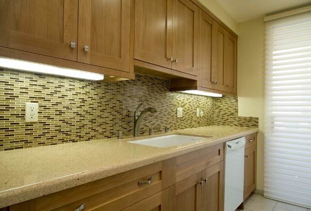 This is an example of a small modern galley separate kitchen in Los Angeles with an undermount sink, shaker cabinets, medium wood cabinets, quartz benchtops, brown splashback, glass tile splashback, white appliances, ceramic floors and no island.