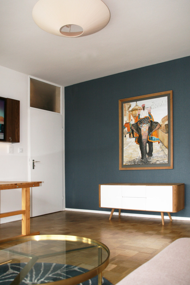 Cette photo montre un petit salon tendance avec un mur bleu, parquet clair, un sol jaune et du papier peint.