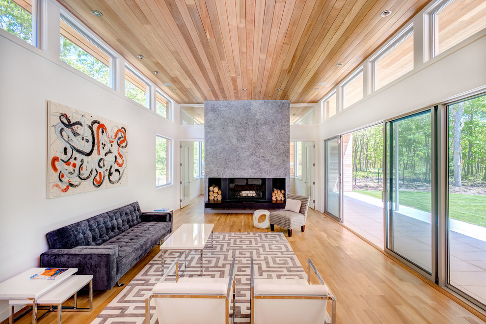 Large modern formal open concept living room in New York with white walls, light hardwood floors, a stone fireplace surround, a two-sided fireplace, no tv and beige floor.