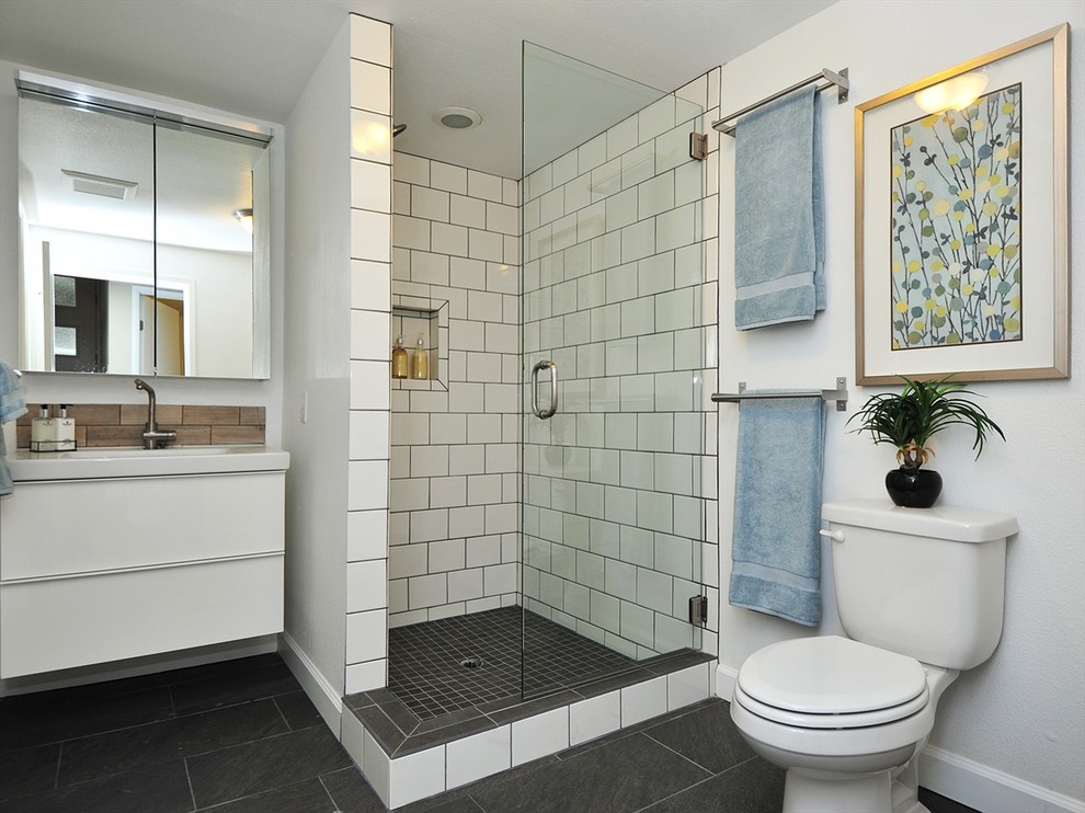 This is an example of a mid-sized modern 3/4 bathroom in Portland with flat-panel cabinets, white cabinets, an alcove shower, a two-piece toilet, black and white tile, porcelain tile, white walls, porcelain floors and an integrated sink.