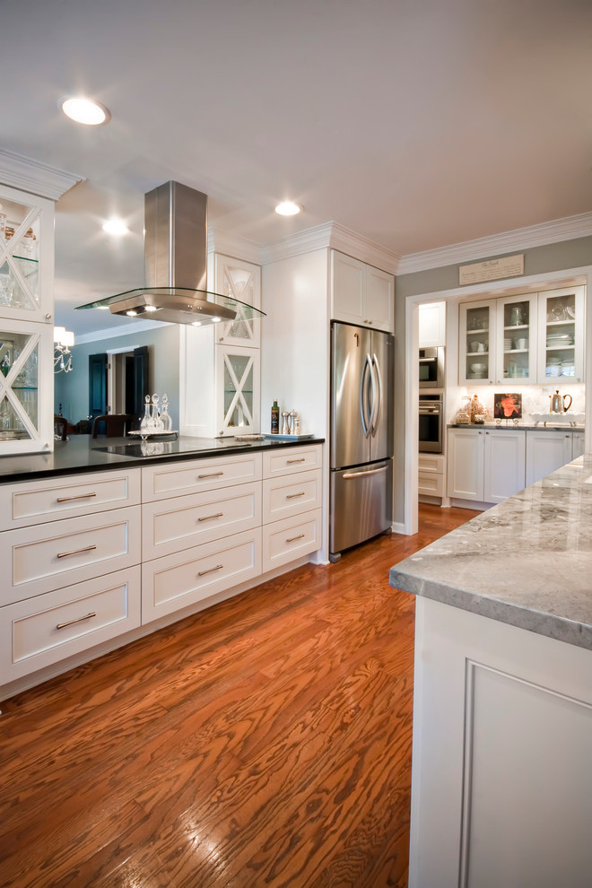 Inspiration for a large transitional galley medium tone wood floor eat-in kitchen remodel with a drop-in sink, glass-front cabinets, white cabinets, onyx countertops, white backsplash, stone tile backsplash and stainless steel appliances