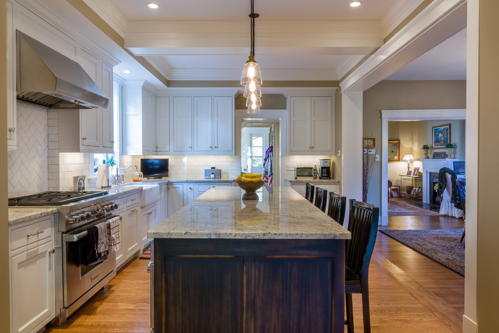 Inspiration for a mid-sized transitional l-shaped light wood floor kitchen remodel in Cincinnati with a farmhouse sink, beaded inset cabinets, white cabinets, granite countertops, white backsplash, porcelain backsplash, white appliances and an island