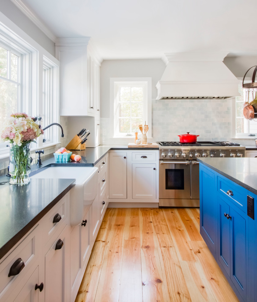 Design ideas for a mid-sized traditional l-shaped kitchen in Boston with shaker cabinets, white cabinets, granite benchtops, porcelain splashback, stainless steel appliances, linoleum floors, with island, a farmhouse sink and orange floor.