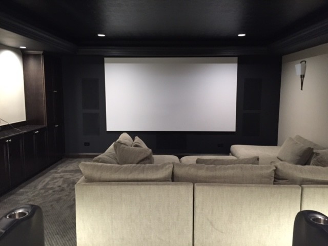 This is an example of a small transitional enclosed home theatre in Chicago with grey walls, carpet and a built-in media wall.