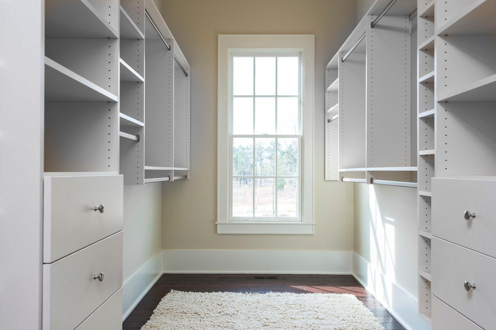 This is an example of a mid-sized arts and crafts gender-neutral walk-in wardrobe in Other with flat-panel cabinets, white cabinets and dark hardwood floors.