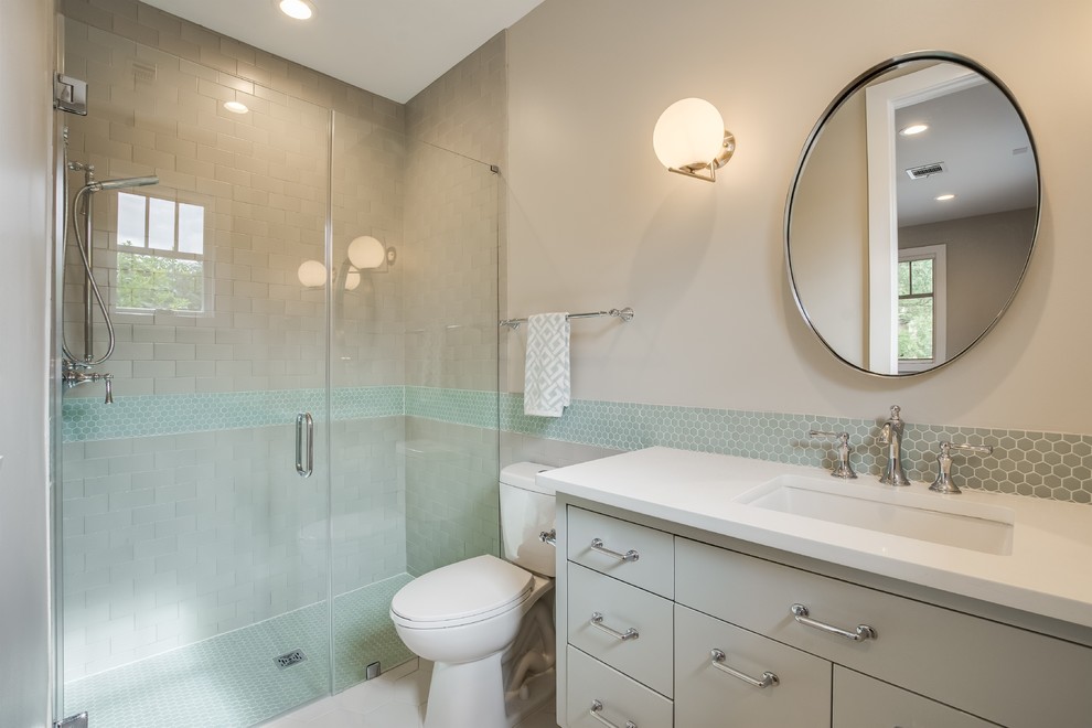 This is an example of a mid-sized midcentury bathroom with shaker cabinets, white cabinets, an alcove shower, a one-piece toilet, multi-coloured tile, mosaic tile, multi-coloured walls, an undermount sink, white floor, a hinged shower door and white benchtops.