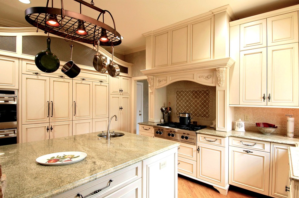 Design ideas for a mid-sized traditional u-shaped eat-in kitchen in DC Metro with an undermount sink, beaded inset cabinets, beige cabinets, granite benchtops, green splashback, glass tile splashback, stainless steel appliances, light hardwood floors, with island and beige floor.