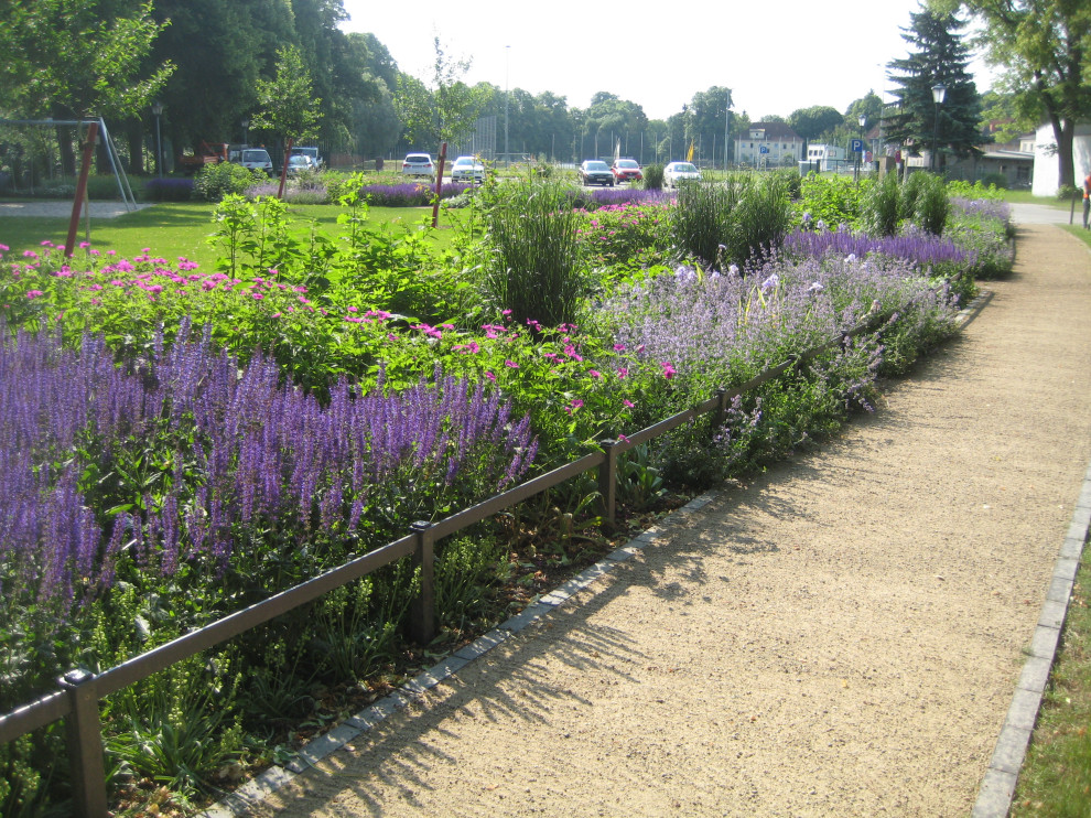 Aménagement d'un grand jardin classique avec un massif de fleurs.