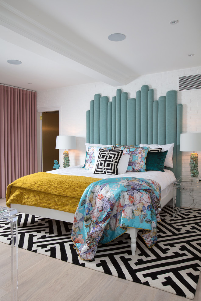 This is an example of a mid-sized eclectic master bedroom in London with white walls and light hardwood floors.