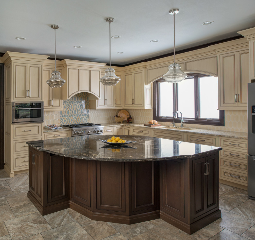 This is an example of a large transitional l-shaped kitchen pantry in Kansas City with an undermount sink, recessed-panel cabinets, beige cabinets, granite benchtops, beige splashback, ceramic splashback, stainless steel appliances, travertine floors, with island and multi-coloured floor.