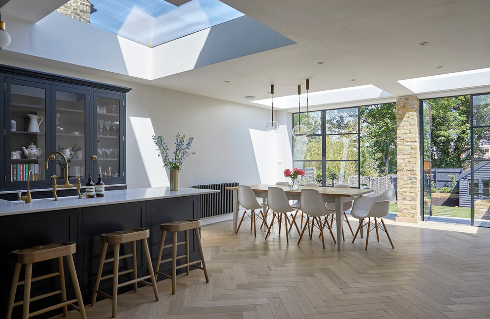 Inspiration for a mid-sized contemporary open plan dining in London with white walls, light hardwood floors and beige floor.