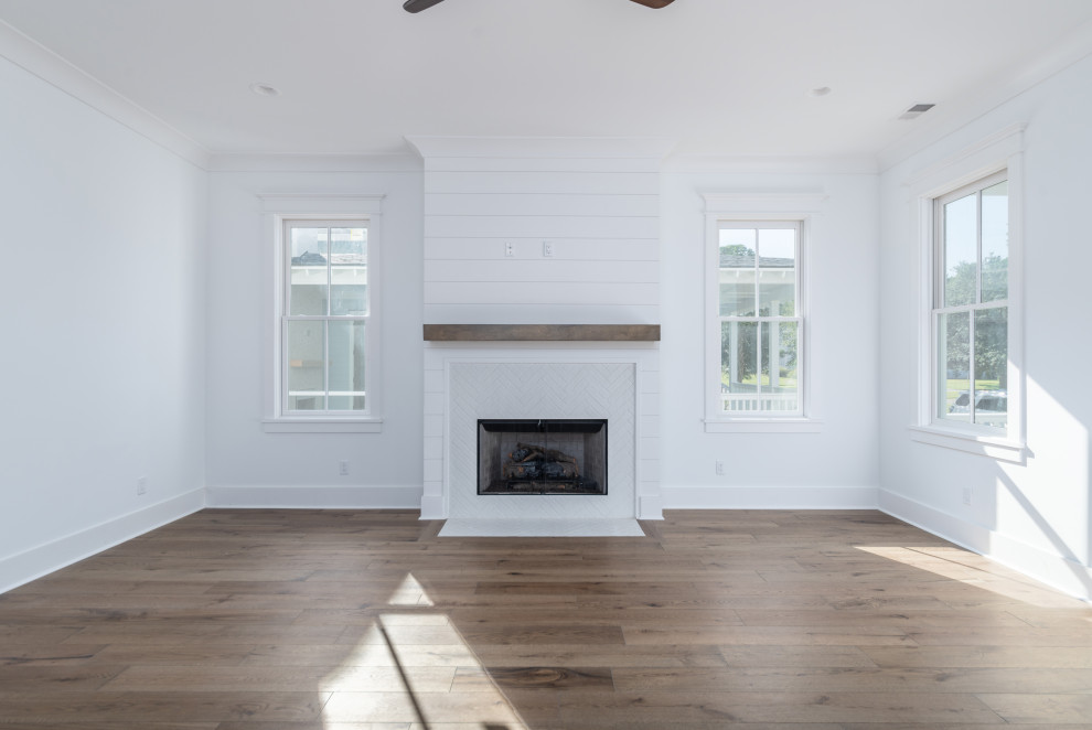 Offenes Klassisches Wohnzimmer mit weißer Wandfarbe, Kamin, gefliester Kaminumrandung und Holzdielenwänden in Sonstige