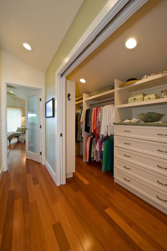 Elegant medium tone wood floor walk-in closet photo in Hawaii with recessed-panel cabinets and white cabinets
