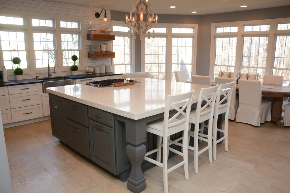 Large transitional u-shaped eat-in kitchen photo in DC Metro with a farmhouse sink, white cabinets, quartz countertops, white backsplash, ceramic backsplash, stainless steel appliances and an island