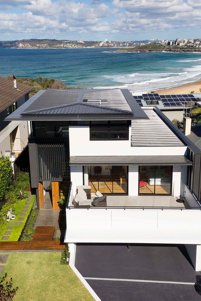 This is an example of a large contemporary three-storey white house exterior in Sydney with a flat roof and a metal roof.