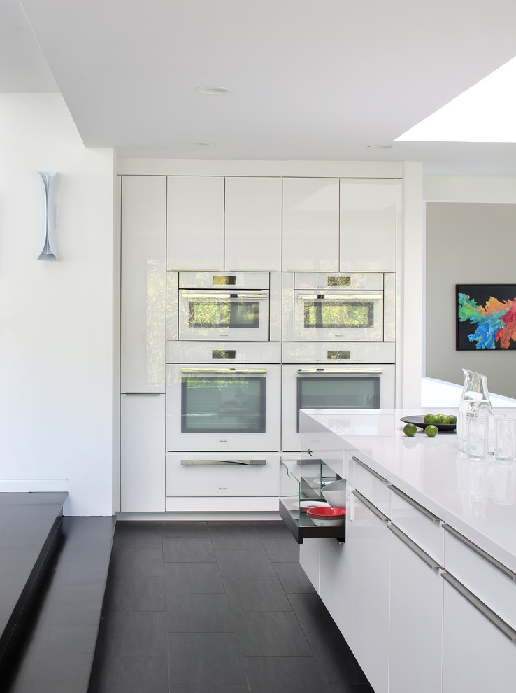 Large trendy porcelain tile eat-in kitchen photo in San Francisco with flat-panel cabinets, white cabinets, white appliances, an island, quartz countertops, red backsplash and glass sheet backsplash