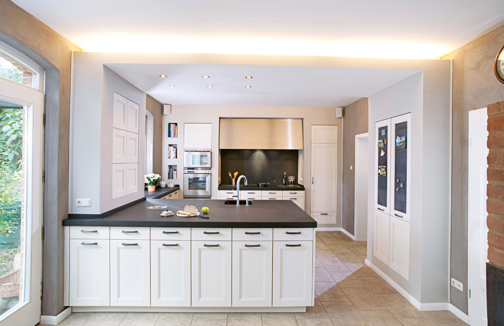Inspiration for an expansive traditional eat-in kitchen in Berlin with an undermount sink, white cabinets, quartz benchtops, black splashback, stone tile splashback, a peninsula, recessed-panel cabinets and stainless steel appliances.