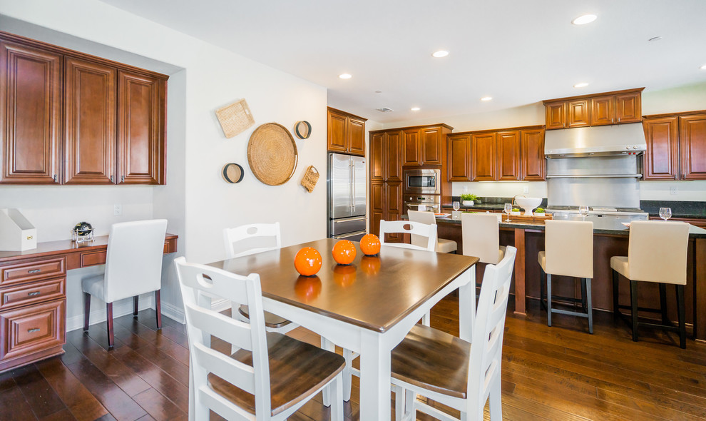 Inspiration for a large transitional u-shaped dark wood floor and brown floor kitchen remodel in Los Angeles with an undermount sink, raised-panel cabinets, medium tone wood cabinets, granite countertops, stainless steel appliances and an island
