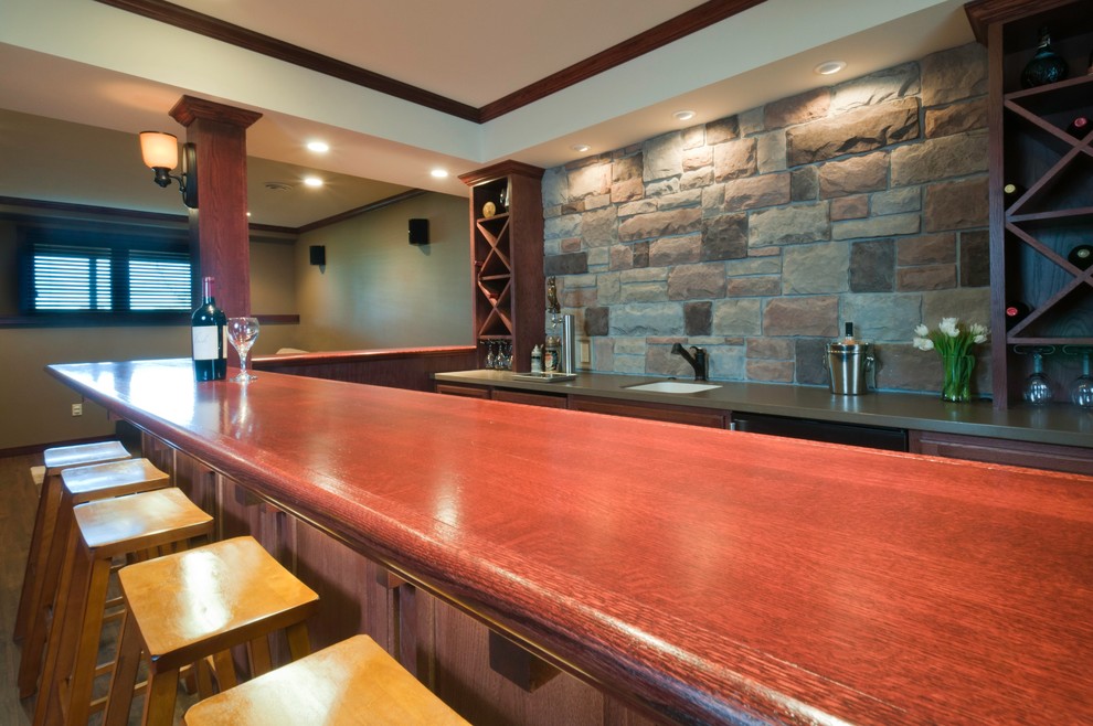 This is an example of a mid-sized traditional l-shaped seated home bar in Other with open cabinets, dark wood cabinets, wood benchtops, multi-coloured splashback, stone tile splashback, dark hardwood floors, an undermount sink, brown floor and brown benchtop.