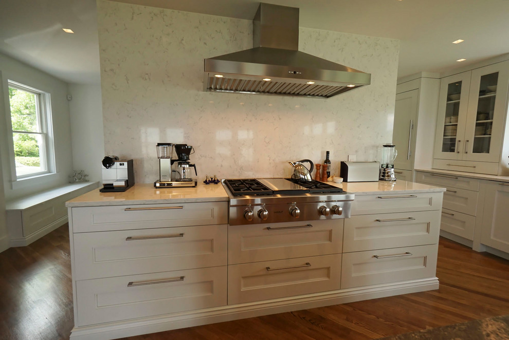 Example of a large transitional l-shaped medium tone wood floor open concept kitchen design in Boston with a double-bowl sink, recessed-panel cabinets, white cabinets, white backsplash, stone slab backsplash, stainless steel appliances and an island