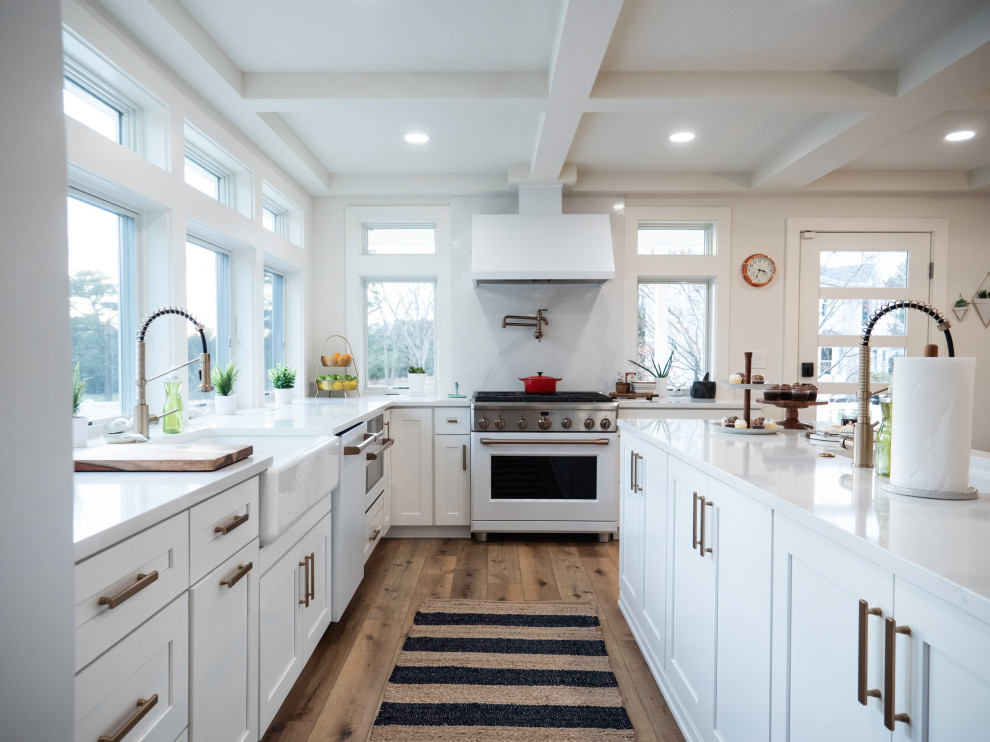 Inspiration for a transitional l-shaped kitchen in Philadelphia with a farmhouse sink, shaker cabinets, white cabinets, white appliances, medium hardwood floors, with island, brown floor, white benchtop and coffered.
