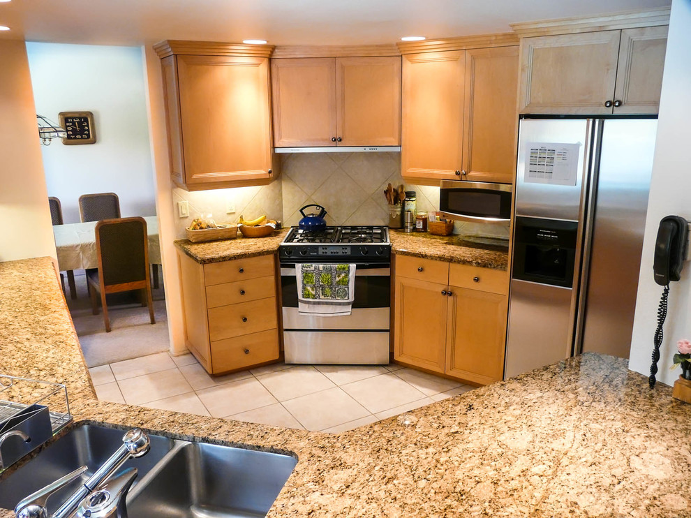Example of a mid-sized transitional l-shaped porcelain tile enclosed kitchen design in San Diego with an undermount sink, recessed-panel cabinets, light wood cabinets, granite countertops, beige backsplash, porcelain backsplash, stainless steel appliances and no island