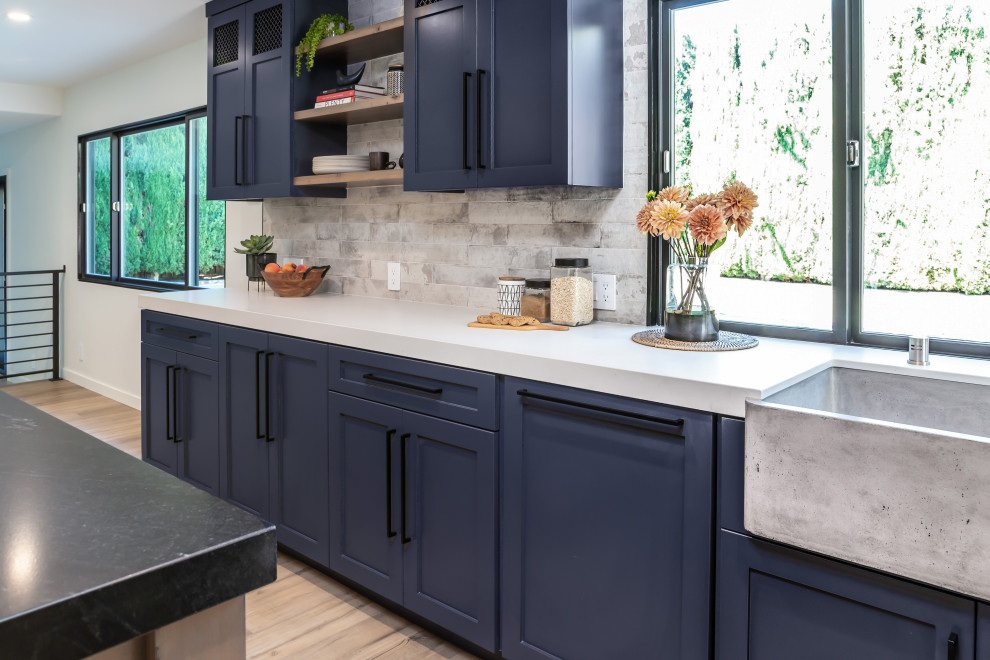 Inspiration for a large industrial l-shaped eat-in kitchen in San Francisco with an undermount sink, shaker cabinets, black cabinets, granite benchtops, stone slab splashback, stainless steel appliances, laminate floors, with island, brown floor and black benchtop.