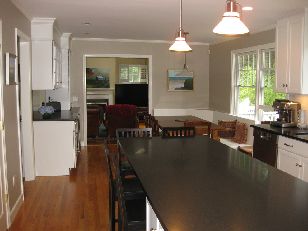 Eat-in kitchen - transitional u-shaped medium tone wood floor eat-in kitchen idea in Boston with an undermount sink, recessed-panel cabinets, white cabinets, gray backsplash, subway tile backsplash, stainless steel appliances, an island and black countertops