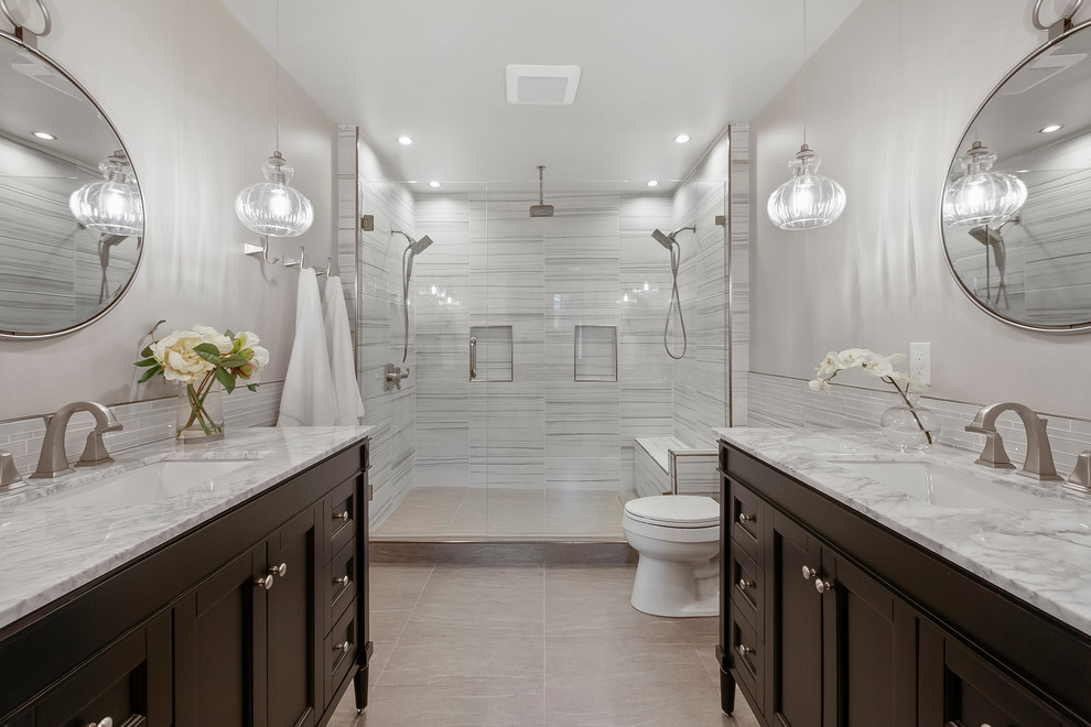 Mid-sized transitional master wet room bathroom in Austin with furniture-like cabinets, black cabinets, a two-piece toilet, gray tile, ceramic tile, white walls, ceramic floors, an undermount sink, marble benchtops, grey floor, a hinged shower door and white benchtops.