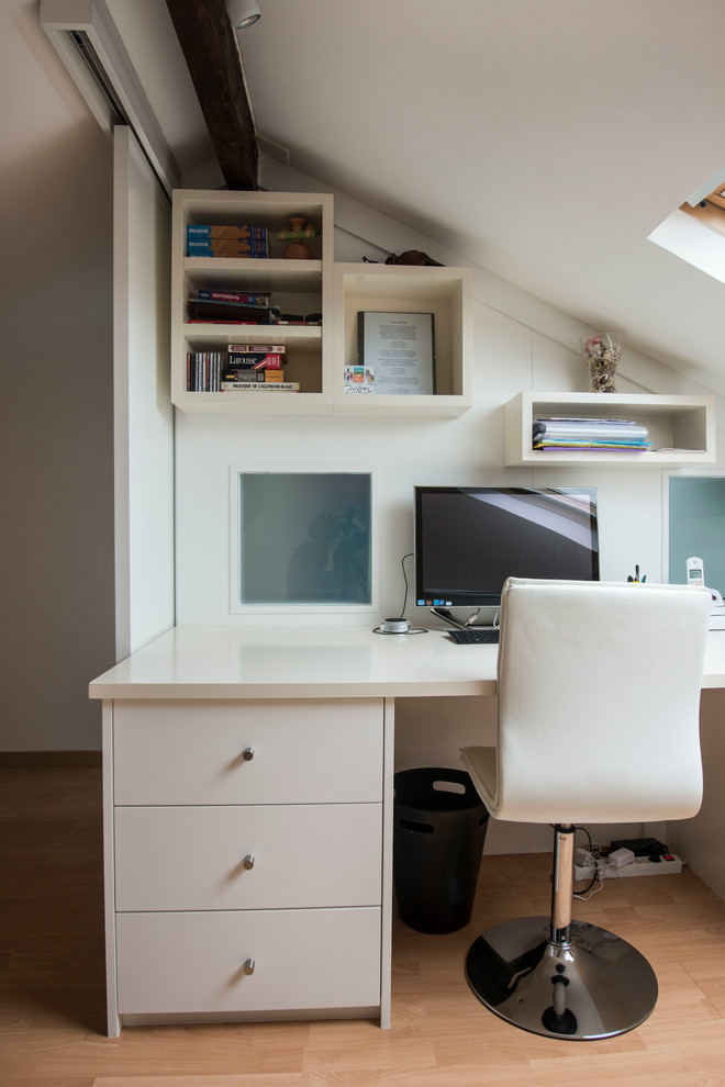 Photo of a small contemporary study room in Paris with white walls, light hardwood floors and a built-in desk.