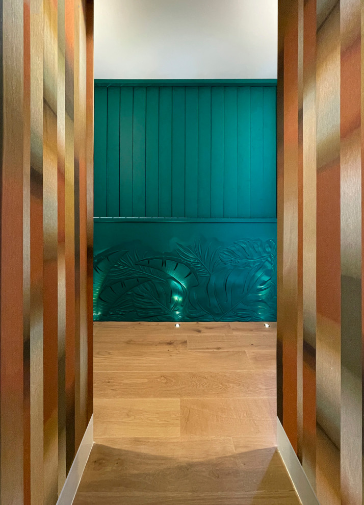 Modelo de recibidores y pasillos exóticos de tamaño medio con paredes verdes, suelo de madera en tonos medios, suelo marrón, panelado y iluminación