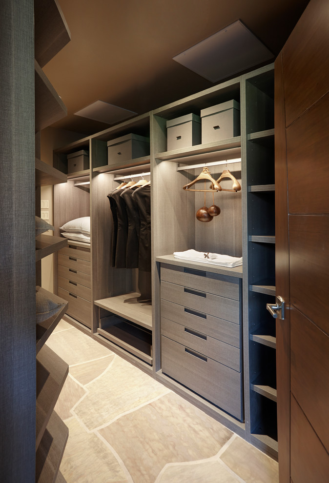 Inspiration for a large gender-neutral dressing room in Other with flat-panel cabinets, limestone floors, grey floor and grey cabinets.