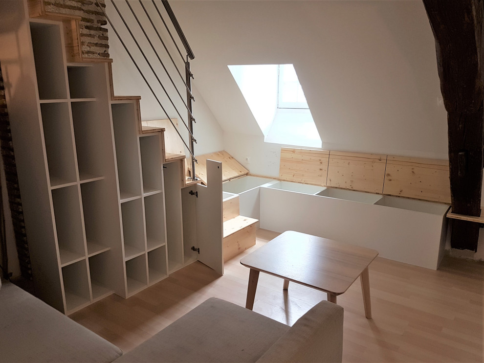 Modelo de sala de estar tipo loft tradicional pequeña sin chimenea con paredes blancas, suelo de madera clara, suelo marrón, vigas vistas y ladrillo