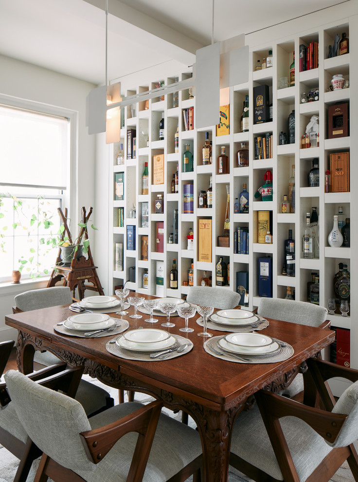 Aménagement d'une salle à manger classique avec un mur blanc, un sol en bois brun et poutres apparentes.