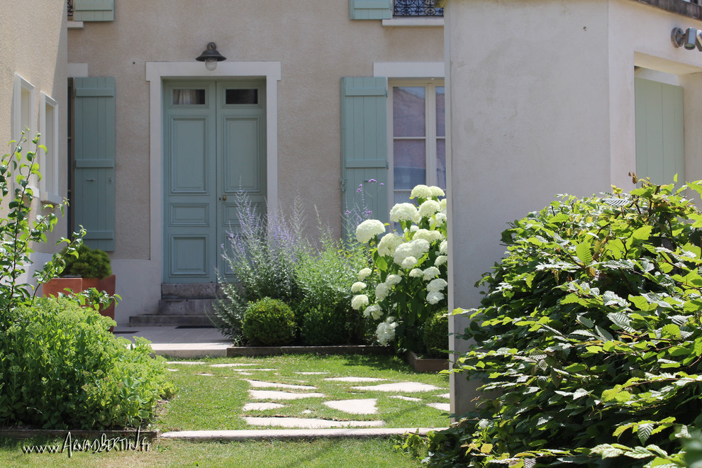 Ejemplo de jardín de estilo de casa de campo de tamaño medio con exposición parcial al sol y adoquines de piedra natural
