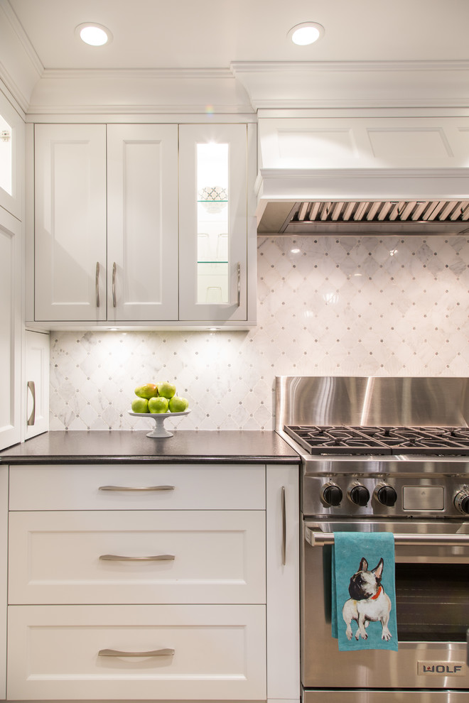 Example of a large transitional l-shaped medium tone wood floor and beige floor eat-in kitchen design in Vancouver with an undermount sink, shaker cabinets, white cabinets, granite countertops, gray backsplash, marble backsplash, stainless steel appliances, an island and black countertops