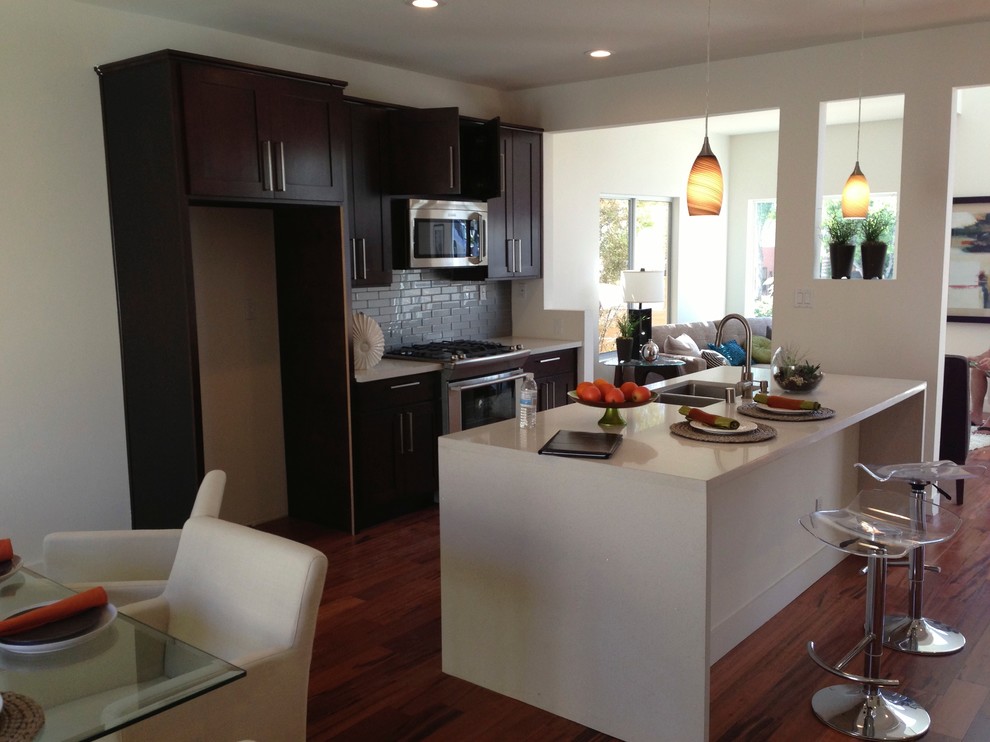 This is an example of a large transitional kitchen in San Diego with a double-bowl sink, shaker cabinets, dark wood cabinets, quartz benchtops, medium hardwood floors, with island and brown floor.