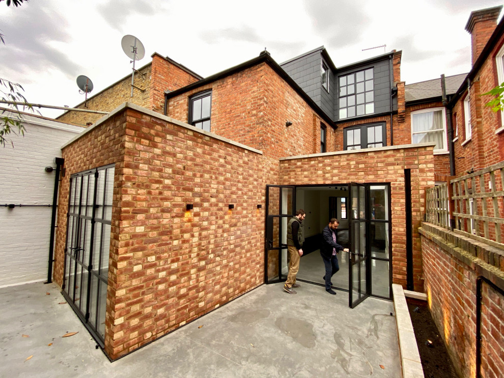 Large contemporary three-storey brick black townhouse exterior in London with a gambrel roof, a tile roof and a black roof.
