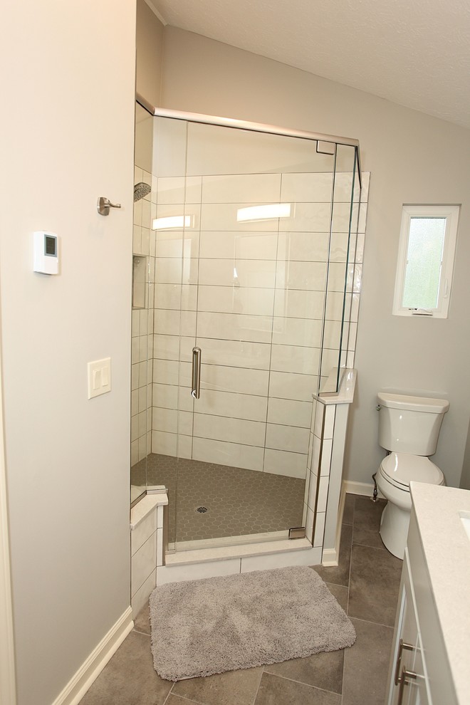 Corner shower - mid-sized transitional master ceramic tile porcelain tile and brown floor corner shower idea in Indianapolis with recessed-panel cabinets, gray walls, a drop-in sink and a hinged shower door