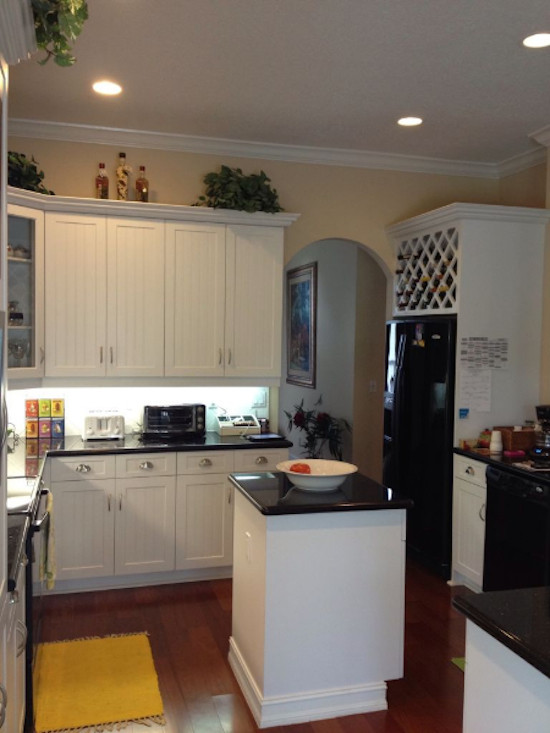 Example of a mid-sized u-shaped medium tone wood floor eat-in kitchen design in Miami with a double-bowl sink, shaker cabinets, white cabinets, white backsplash, black appliances and an island