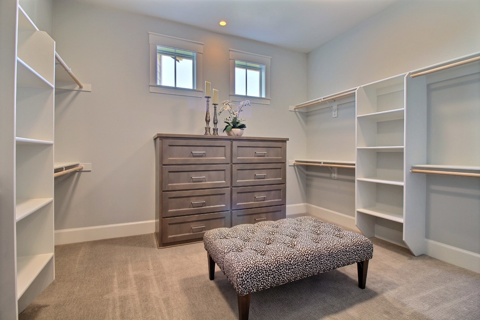 This is an example of an expansive arts and crafts gender-neutral walk-in wardrobe in Portland with open cabinets, white cabinets, carpet and beige floor.